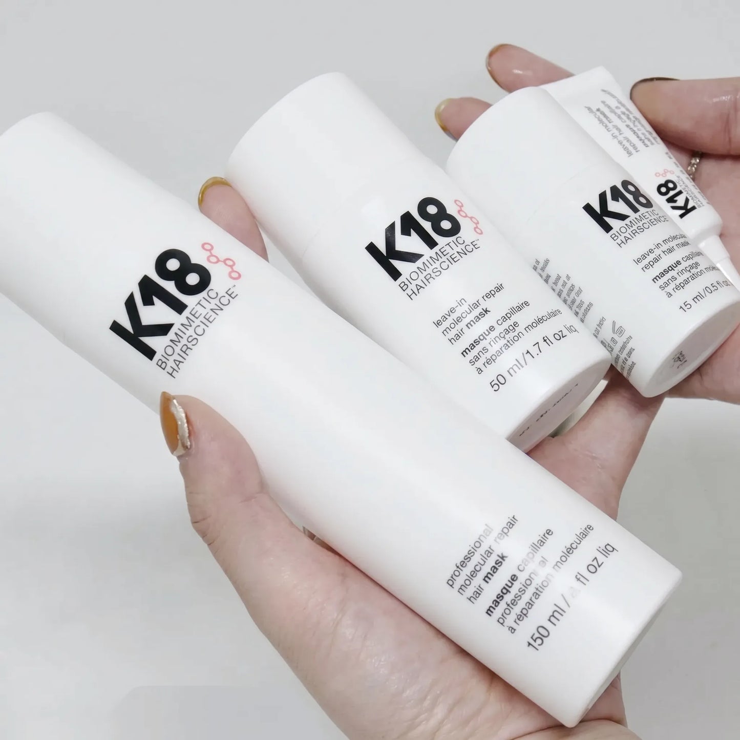 Hand holding K18 hair mask product set with 150ml bottle, 50ml bottle and 15ml tube