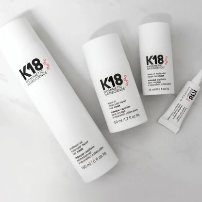 K18 Molecular Repair Hair Mask product set with 150ml, 50ml, 15ml and tube on marble background