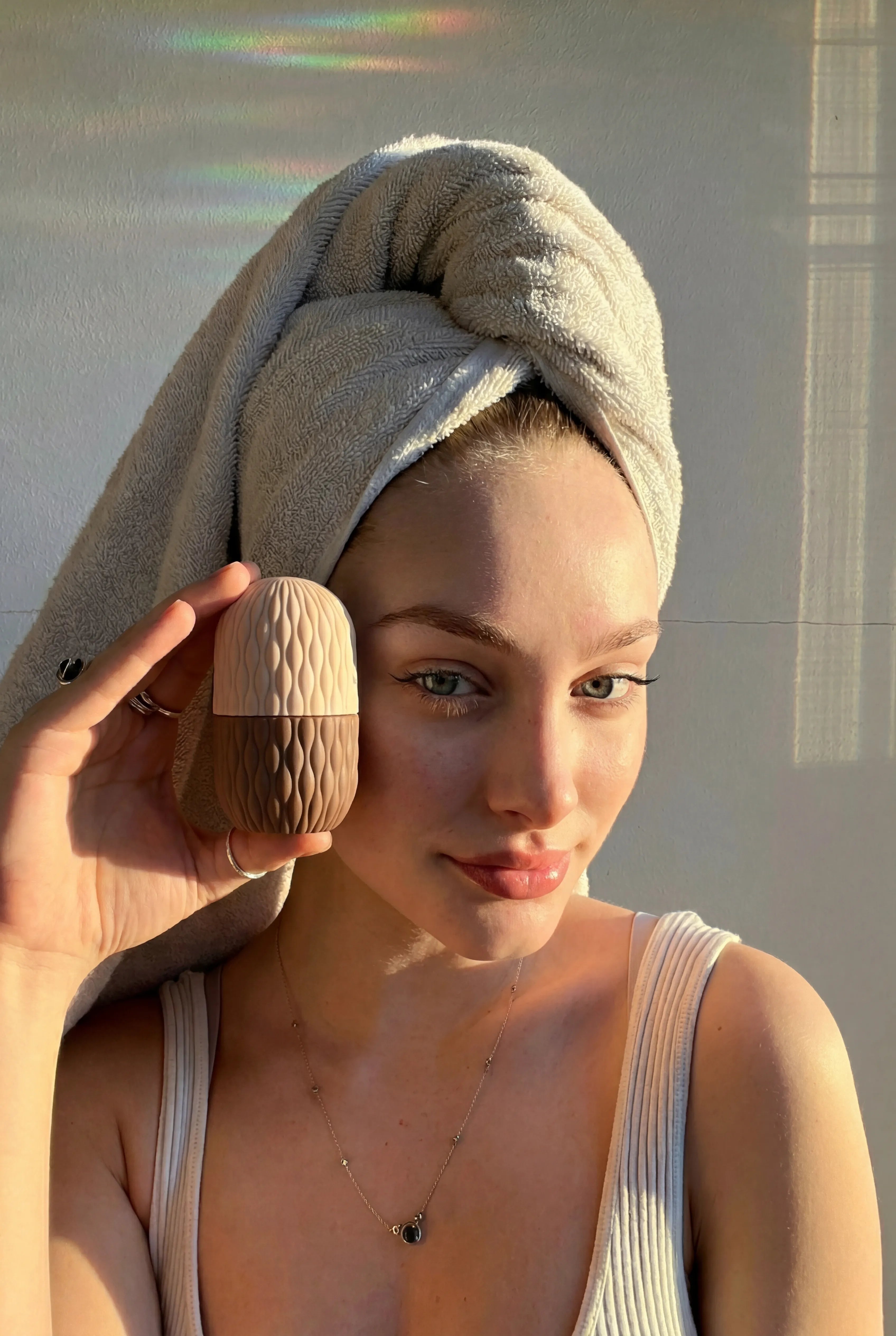 Woman holding beige Velivor Glace Ice Roller during morning skincare routine